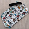 White pouch with tattoo-style design on a wooden surface