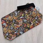 Colorful patterned pouch with a black strap on a light wooden surface
