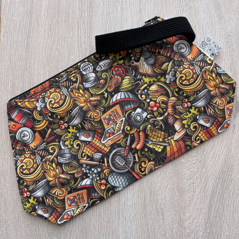 Colorful patterned pouch with a black strap on a light wooden surface