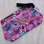 Pink pouch with colorful designs on a light wooden surface