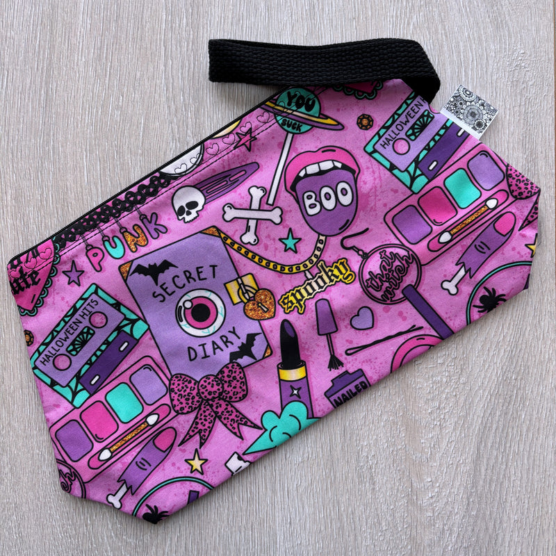 Pink pouch with colorful designs on a light wooden surface