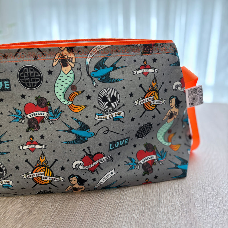 Pouch with tattoo-themed design on a light surface