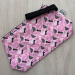Pink pouch with black text pattern on a gray surface