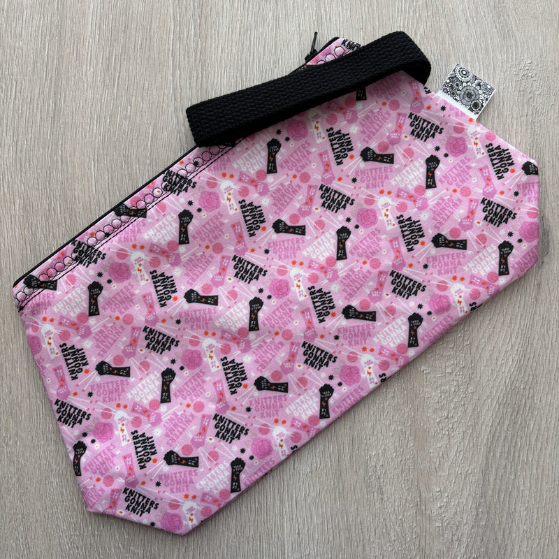 Pink pouch with black text pattern on a gray surface