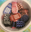 a bowl of many small pairs of colourwork knit mittens in various colours