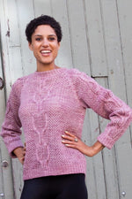 a woman wearing a pink knit sweater with cables
