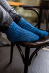 feet on a chair wearing blue knit socks