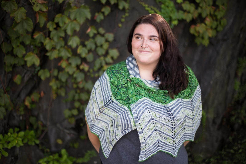 brunette woman wearing a patterned knit shawl in green, grey, and blue