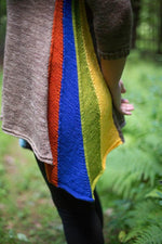 a woman holding a colourful colourblocked knit shawl