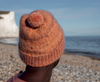 woman on a beach wearing a subtly cabled hat in orange