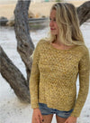 blonde woman standing in front of a tree wearing a yellow textured knit sweater