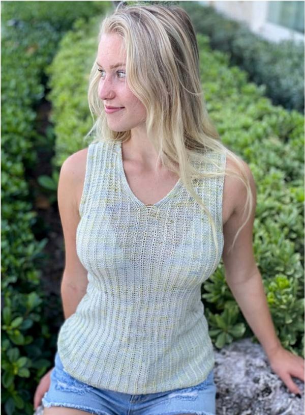 blonde woman standing in front of bushes wearing a neutral knit sleeveless top